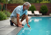 Conseils pour éviter l’algue moutarde dans votre piscine Homme d'âge moyen testant l'eau de la piscine extérieure