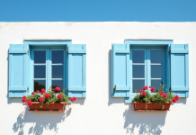 Façade d'une maison méditerranéenne avec volets bleus fermés et fleurs