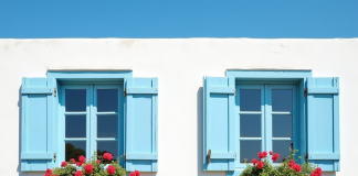 Façade d'une maison méditerranéenne avec volets bleus fermés et fleurs